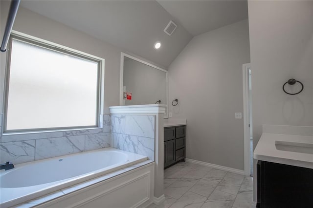 bathroom with a bathing tub, vanity, and lofted ceiling