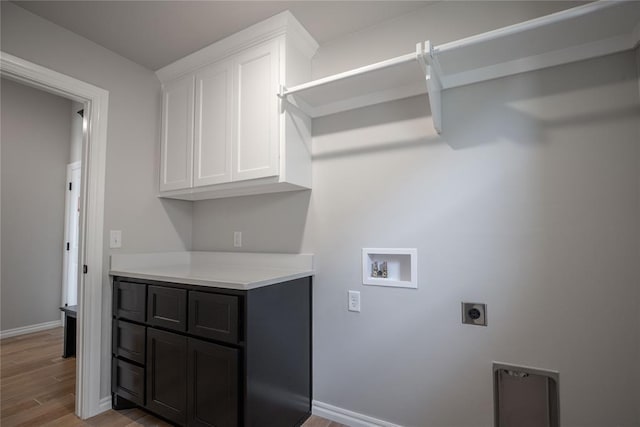 laundry area with cabinets, hookup for a washing machine, light hardwood / wood-style floors, and electric dryer hookup