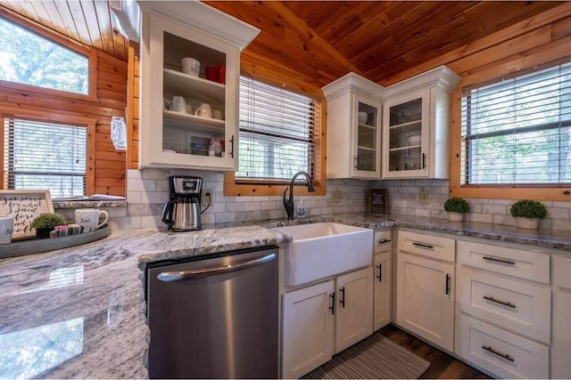 kitchen with wood walls, dishwasher, white cabinets, and vaulted ceiling