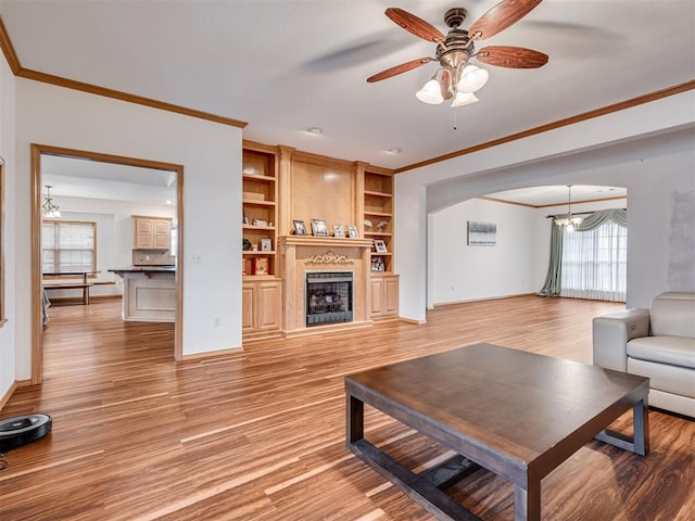 living room featuring ceiling fan with notable chandelier, light hardwood / wood-style floors, crown molding, and a healthy amount of sunlight