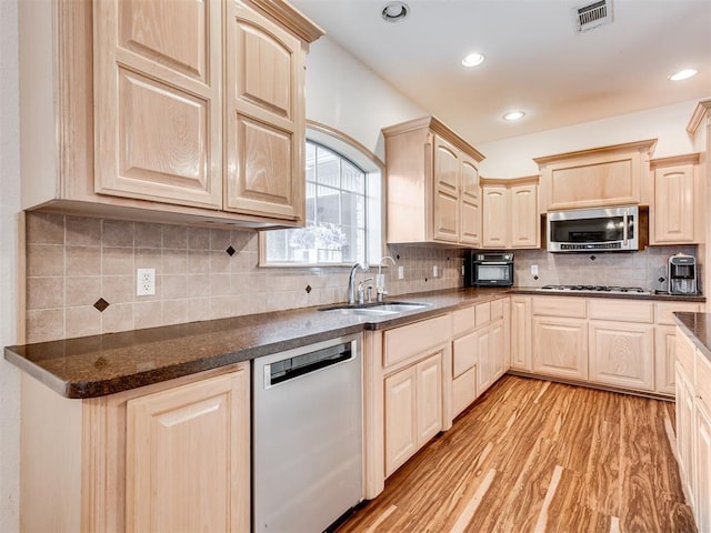 kitchen with sink, light brown cabinets, stainless steel appliances, decorative backsplash, and light wood-type flooring