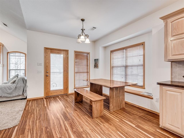 unfurnished dining area with light wood-type flooring and an inviting chandelier