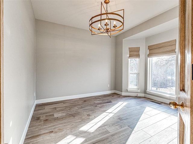 spare room featuring a notable chandelier and light hardwood / wood-style floors