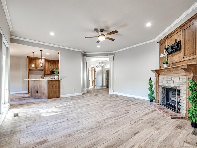 living room with ceiling fan with notable chandelier, crown molding, light wood-type flooring, and a fireplace