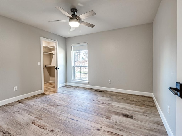 unfurnished bedroom featuring ceiling fan, light hardwood / wood-style floors, and a spacious closet