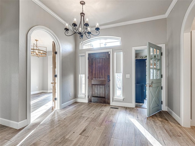 entrance foyer with a chandelier, ornamental molding, and light hardwood / wood-style flooring