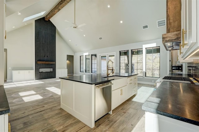 kitchen with high vaulted ceiling, a spacious island, light hardwood / wood-style flooring, stainless steel dishwasher, and white cabinetry