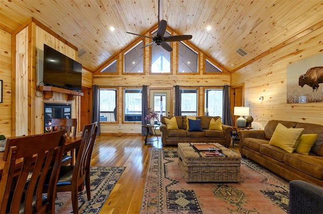 living room with light hardwood / wood-style floors, plenty of natural light, wooden walls, and ceiling fan