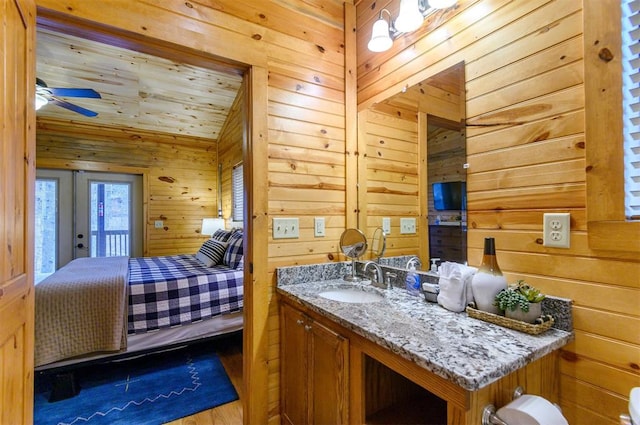 interior space with ceiling fan, wood walls, vanity, and hardwood / wood-style flooring