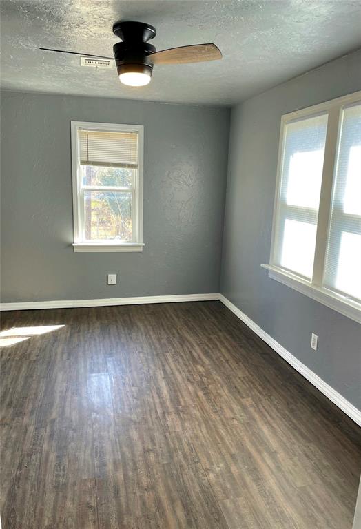 unfurnished room featuring a textured ceiling, ceiling fan, and dark wood-type flooring