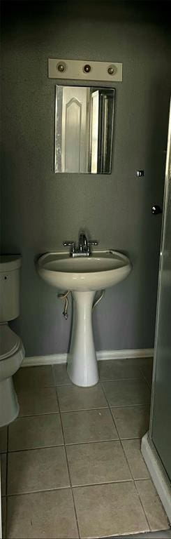 bathroom featuring tile patterned flooring, toilet, and walk in shower