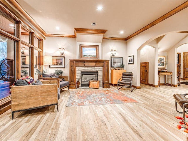 living room featuring crown molding, a fireplace, and light hardwood / wood-style floors