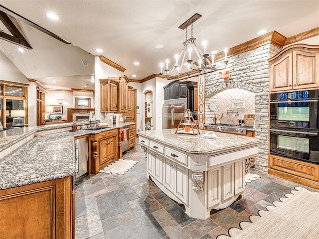 kitchen featuring a large island, light stone countertops, stainless steel appliances, a chandelier, and decorative light fixtures