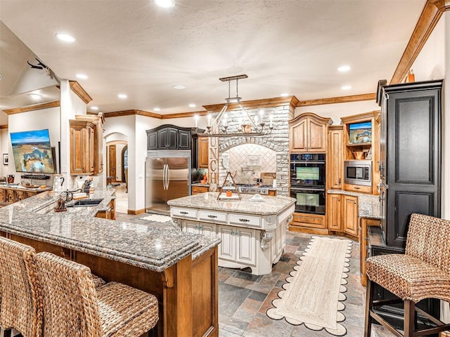 kitchen with a breakfast bar, sink, built in appliances, a kitchen island, and kitchen peninsula