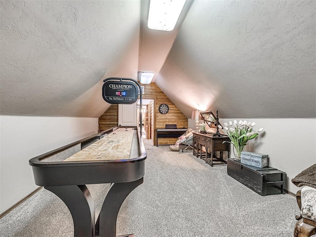 recreation room with carpet, a textured ceiling, lofted ceiling, and wood walls