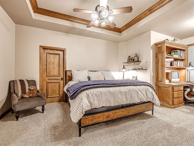 bedroom featuring a tray ceiling, ceiling fan, carpet flooring, and crown molding