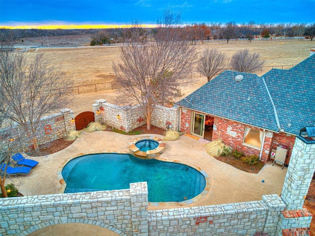 pool at dusk with an in ground hot tub and a patio