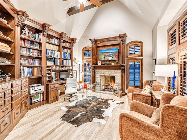 sitting room with high vaulted ceiling, light hardwood / wood-style flooring, ceiling fan, and a stone fireplace