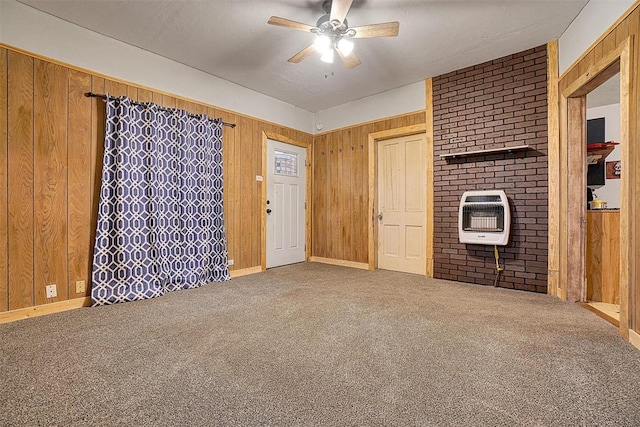 unfurnished living room with carpet floors, heating unit, ceiling fan, and wooden walls