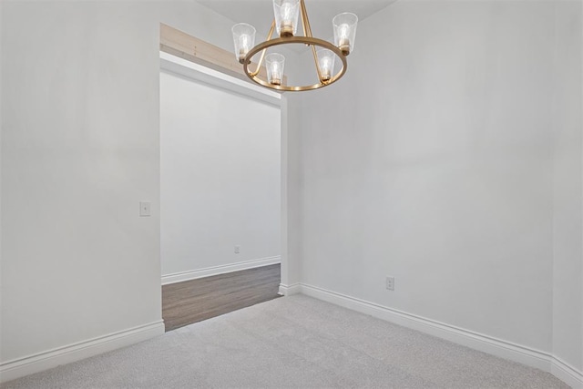 spare room featuring carpet floors and a chandelier