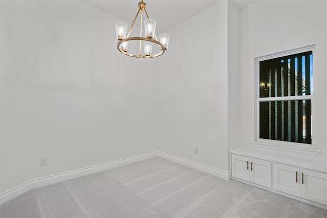 carpeted empty room with an inviting chandelier