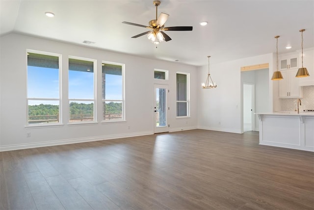 unfurnished living room with dark hardwood / wood-style floors, sink, and ceiling fan with notable chandelier