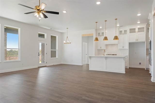 kitchen featuring an island with sink, dark wood-type flooring, and decorative light fixtures