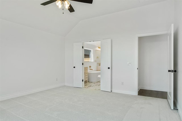 unfurnished bedroom with ensuite bath, ceiling fan, light carpet, and vaulted ceiling