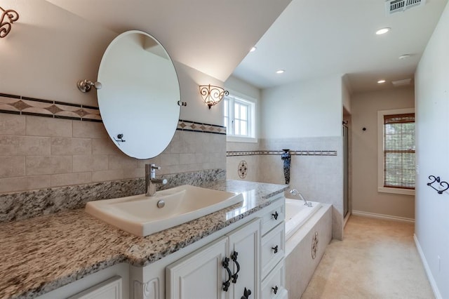 bathroom with vanity and a relaxing tiled tub