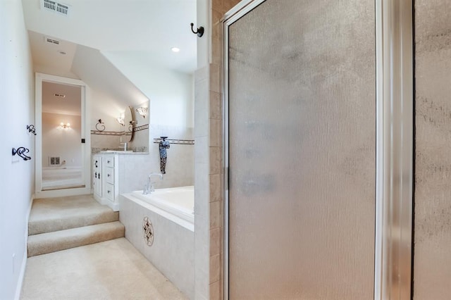 bathroom featuring vanity, independent shower and bath, and vaulted ceiling