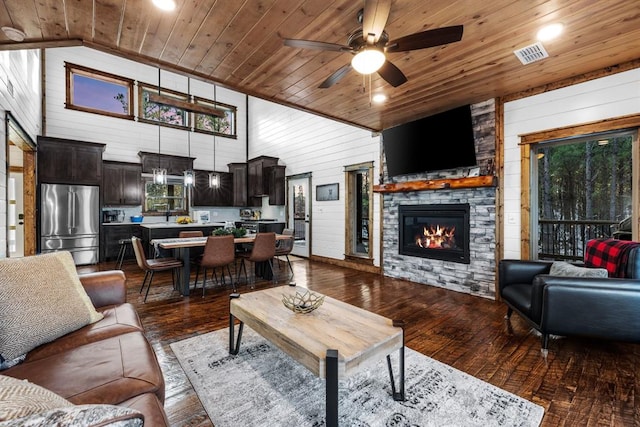 living room featuring ceiling fan, dark wood-type flooring, wood ceiling, and wooden walls