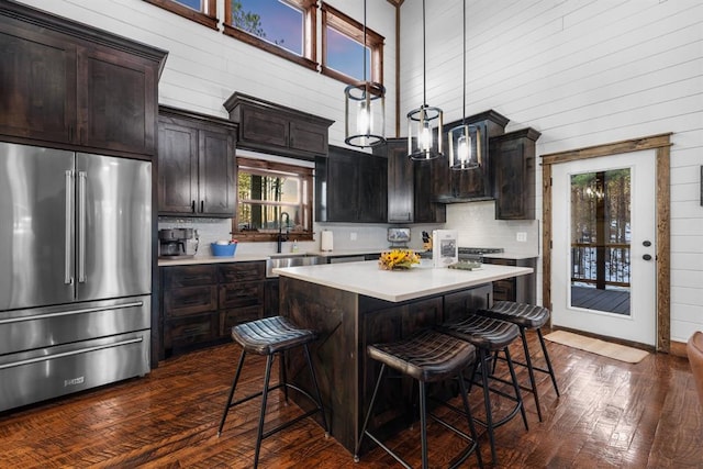 kitchen with hanging light fixtures, a high ceiling, dark wood-type flooring, and high quality fridge