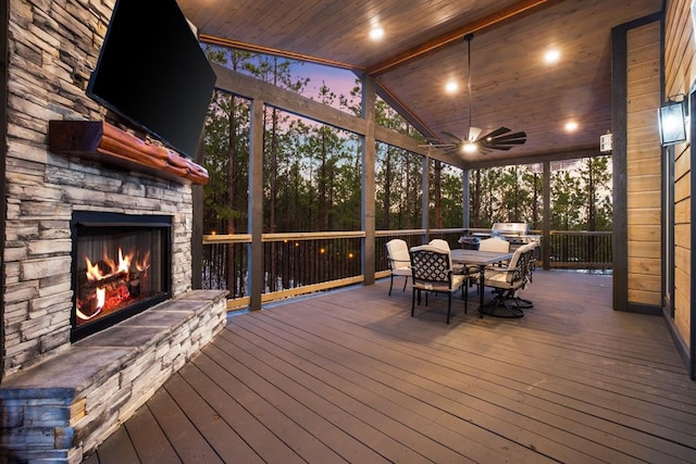 unfurnished sunroom with ceiling fan, an outdoor stone fireplace, wood ceiling, and vaulted ceiling