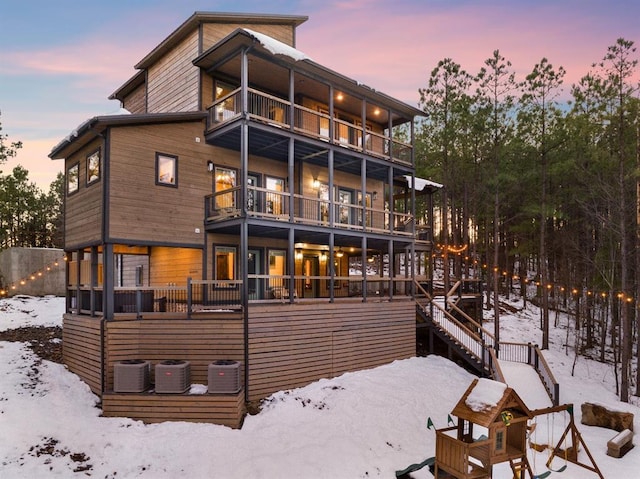 snow covered property with cooling unit and a balcony