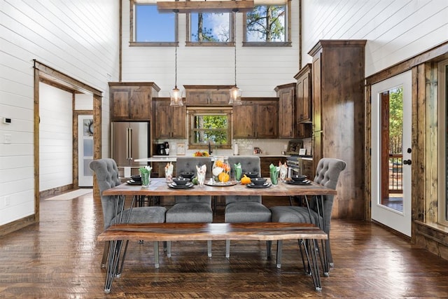 kitchen with high quality fridge, dark brown cabinets, a healthy amount of sunlight, and a high ceiling