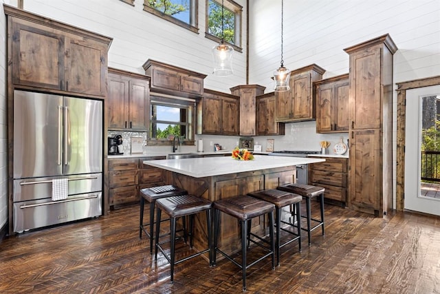 kitchen with pendant lighting, a high ceiling, a wealth of natural light, premium appliances, and a kitchen island