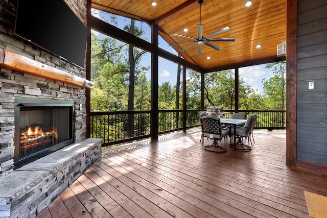 sunroom / solarium featuring an outdoor stone fireplace, ceiling fan, wooden ceiling, and vaulted ceiling