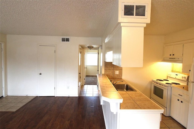 kitchen with electric range, sink, a textured ceiling, tile counters, and white cabinets