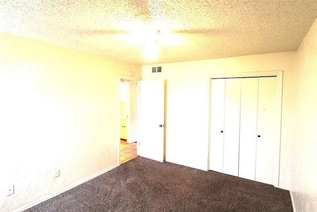 unfurnished bedroom with light carpet, ceiling fan, a closet, and a textured ceiling