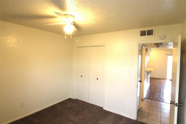 unfurnished bedroom with a textured ceiling, ceiling fan, a closet, and light colored carpet