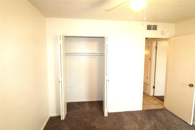 unfurnished bedroom with ceiling fan, a textured ceiling, a closet, and light carpet