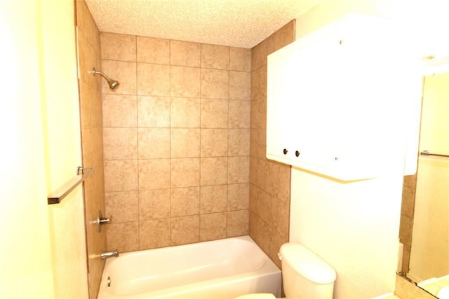 bathroom featuring toilet, tiled shower / bath combo, and a textured ceiling