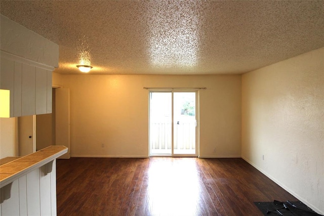 spare room with a textured ceiling and dark wood-type flooring