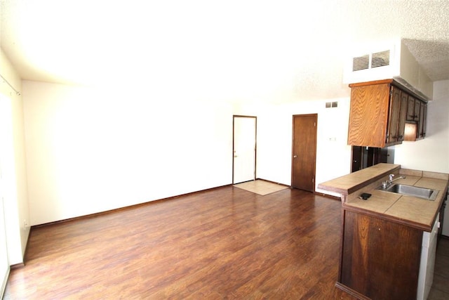 kitchen featuring a textured ceiling, dark hardwood / wood-style flooring, kitchen peninsula, and sink