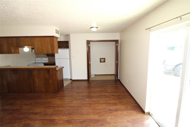 kitchen with kitchen peninsula, a textured ceiling, dark hardwood / wood-style flooring, white refrigerator, and range