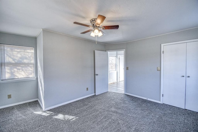 unfurnished bedroom featuring dark colored carpet, a closet, and ceiling fan