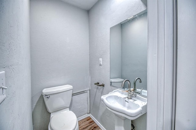 bathroom with toilet, wood-type flooring, and sink