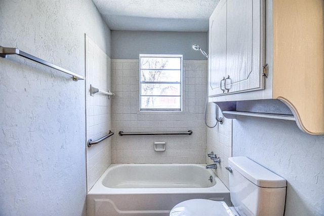 bathroom with a textured ceiling, toilet, and tiled shower / bath