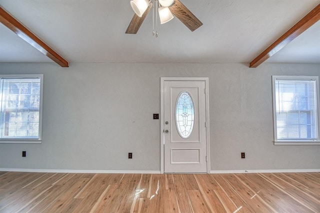 foyer entrance featuring beamed ceiling, ceiling fan, a healthy amount of sunlight, and wood-type flooring