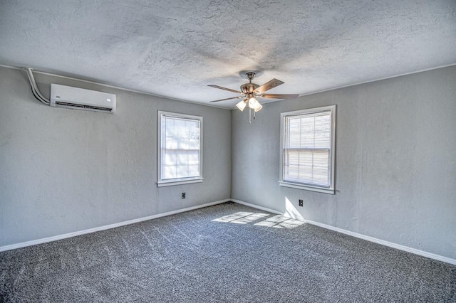 carpeted empty room with an AC wall unit, ceiling fan, a healthy amount of sunlight, and a textured ceiling